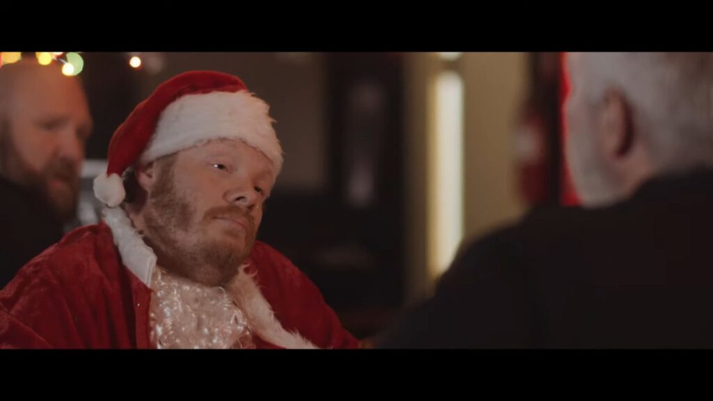 A man dressed as Santa Claus sitting in a bar in 13 Slays Till X-Mas (2020), a scuzzy anthology film featured on our list of so-bad-they're-good Christmas horror movies.