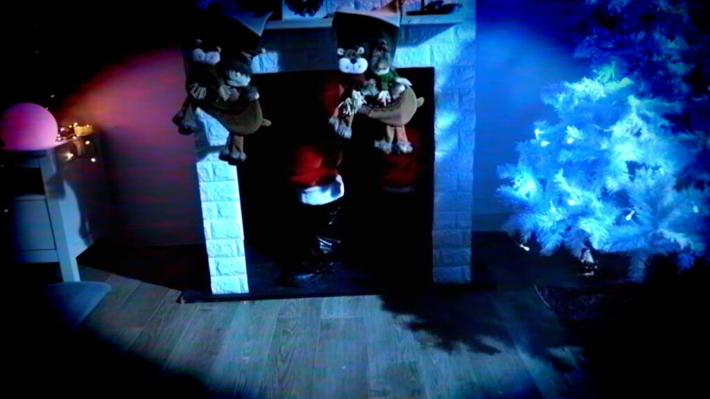Santa's boots appearing in a fireplace next to a bright white tree in Werewolf Santa (2023), a campy entry in the genre of so-bad-they're-good Christmas horror movies.