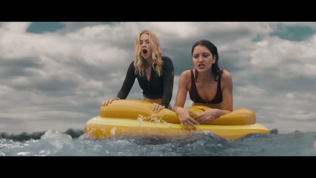 Two women looking terrified and screaming while clinging to a yellow inflatable raft in choppy waters in Killer Whale (2026).