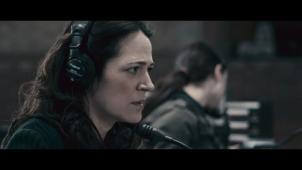 Lisa Houle as Sydney Briar wearing headphones and looking concerned in the radio booth, a character central to the Pontypool (2008) Ending Explained.