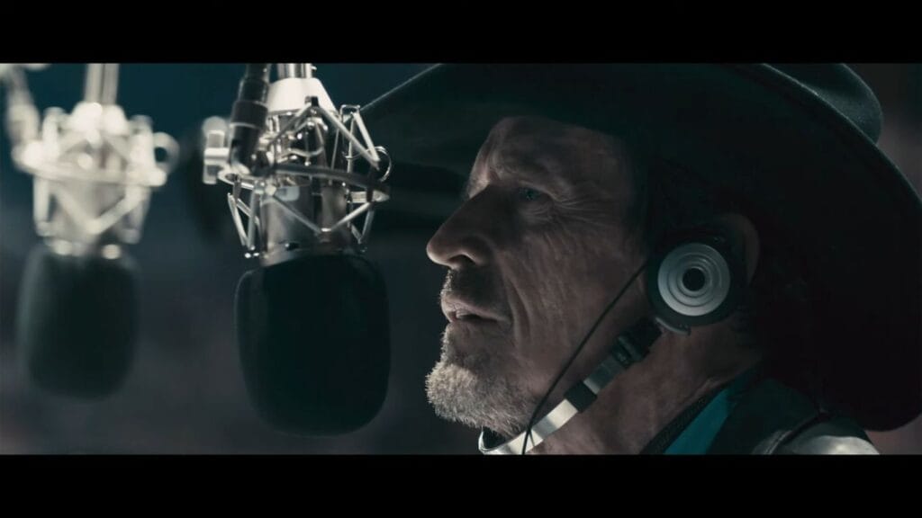 Close-up of Grant Mazzy speaking intensely into a microphone, providing crucial context for the Pontypool (2008) Ending Explained.