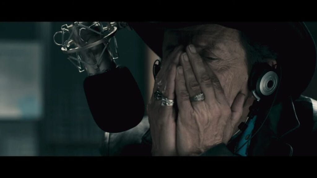 Grant Mazzy with his head in his hands looking distressed in the radio booth, a moment leading up to the Pontypool (2008) Ending Explained.