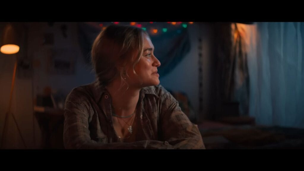 A character looks out a window nervously in the horror movie Primate (2025).