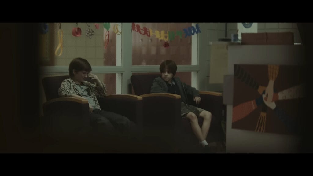 Two young boys sitting in a waiting room, a pivotal moment explained in The Confession (2025).