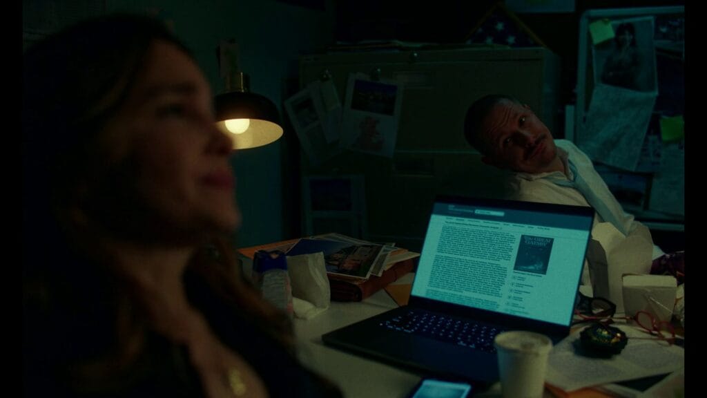 An investigative scene in Twisted (2026) showing a blurred detective in the foreground with a laptop displaying a character analysis of The Great Gatsby, suggesting deeper themes in the film's plot.
