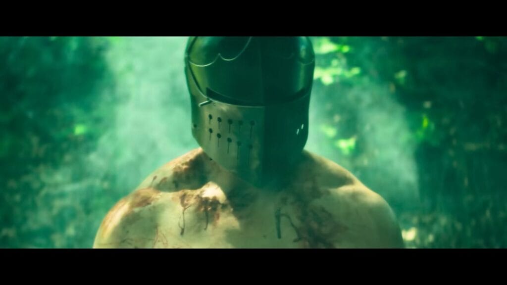 Seamus wearing a medieval knight helmet in a misty forest in the horror movie The Dreadful (2026).