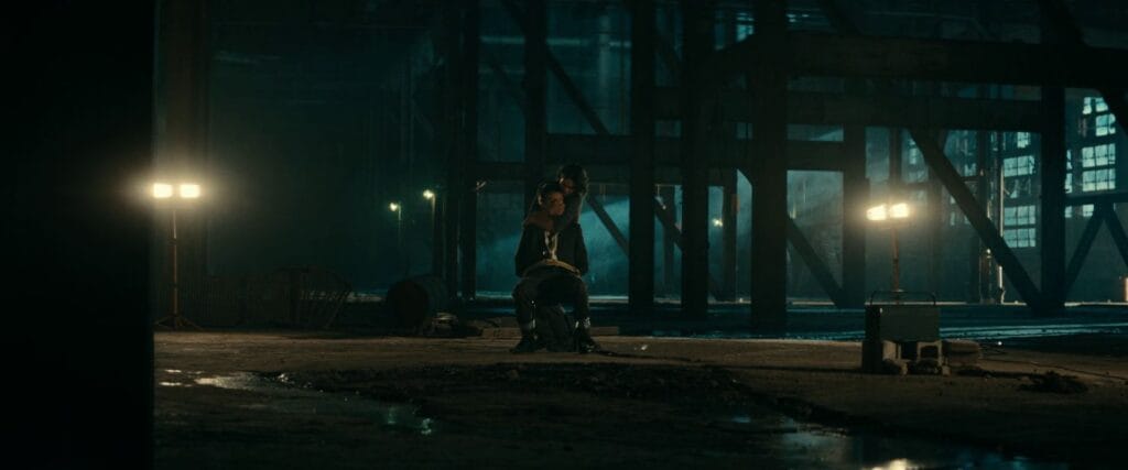 A wide shot of a dark industrial warehouse where Noah is tied to a chair, a pivotal scene from the Whistle (2025) ending explained.
