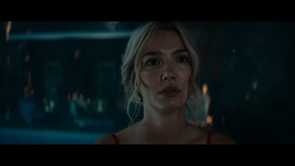 Grace (Ali Skovbye) looks off-camera with a terrified expression in a moody, dimly lit setting from the film Whistle (2025).