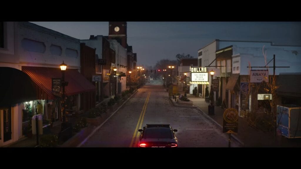 A police car drives down the empty main street of Woodsboro at dusk near the Dallas movie theater in Scream 7.