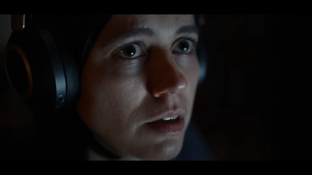 Close-up of a terrified Evy (Nina Kiri) with wide eyes in a dark scene from The Undertone.