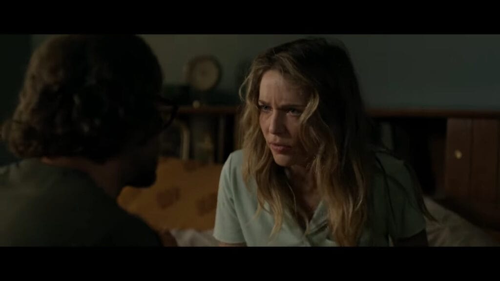 A tense conversation scene from Affection with a frustrated, defensive Jessica Rothe staring down Joseph Cross in a dimly lit bedroom.