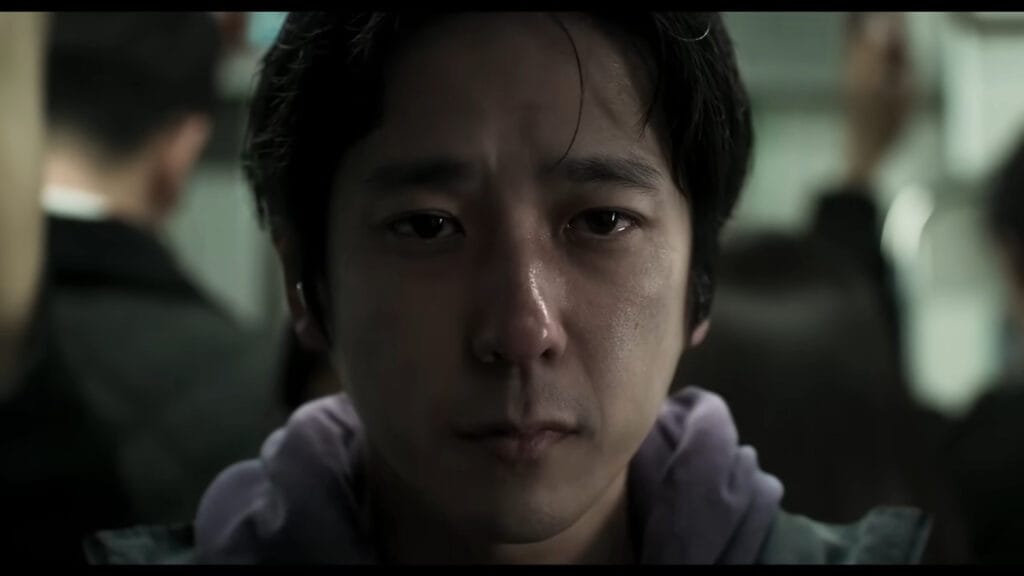 An intense close-up shot of actor Kazunari Ninomiya looking directly into the camera with a stressed and emotional expression in the Japanese horror movie Exit 8.