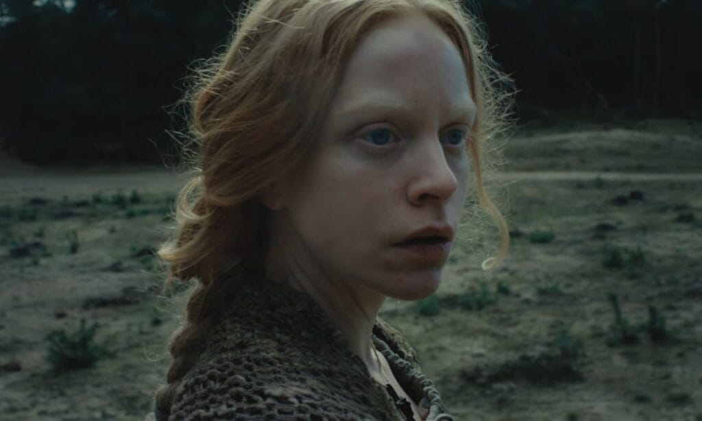 A close-up profile shot of actress Anneke Sluiters as Frieda looking anxious and startled in an open, barren field.
