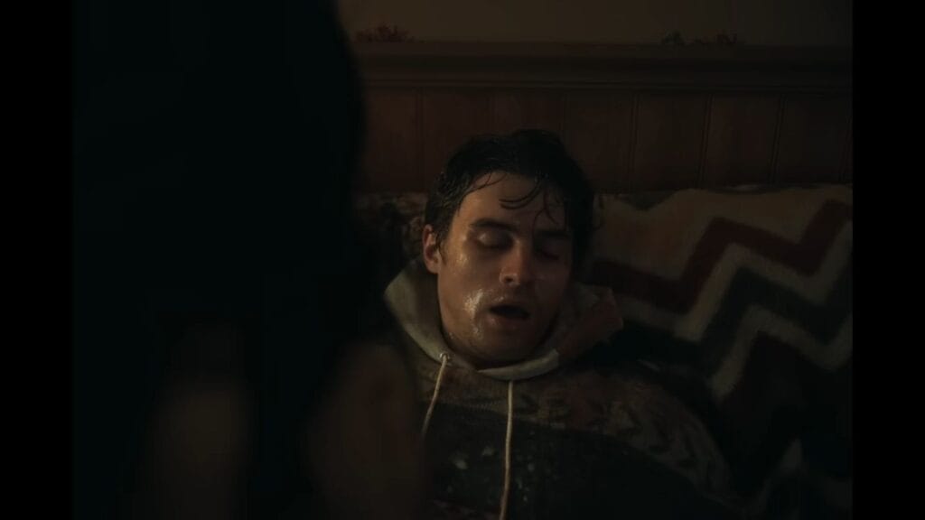 A sweat-drenched and pale Bear lying unconscious or dying on a patterned bedspread in the climax of the film.
