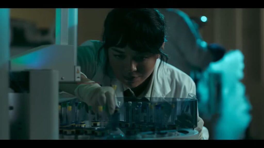 Medical student Hanna wearing gloves and intensely focusing while organizing test tubes in a laboratory under moody teal and green lighting in Saccharine.