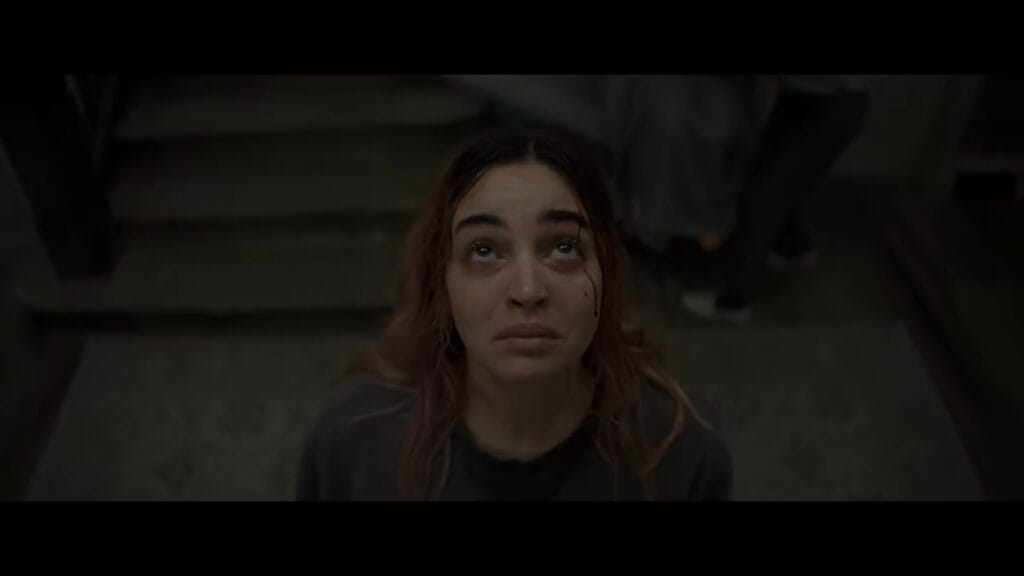 Souheila Yacoub as Alice looking up with tear-filled, anxious eyes and a small trickle of blood on her temple in Evil Dead Burn.