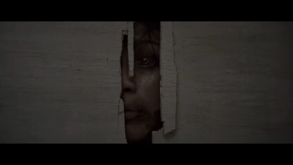 A terrifying close-up shot of a possessed Deadite with glowing eyes peering through a crack in a broken wooden door in Evil Dead Burn.