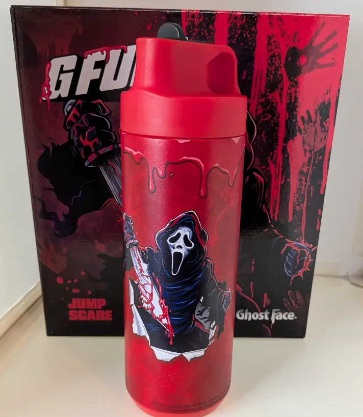 Red G Fuel Ghost Face shaker cup featuring the iconic Scream villain holding a bloody knife, set against the Jump Scare collector's box.