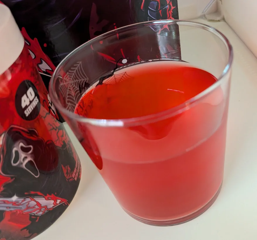 Close-up of a freshly mixed bright red Ghost Face G Fuel energy drink in a clear glass.