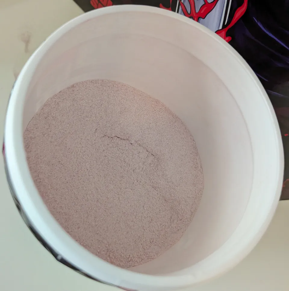 Close-up overhead view of the pale pinkish-white G Fuel Ghost Face Jump Scare energy drink powder inside the tub.
