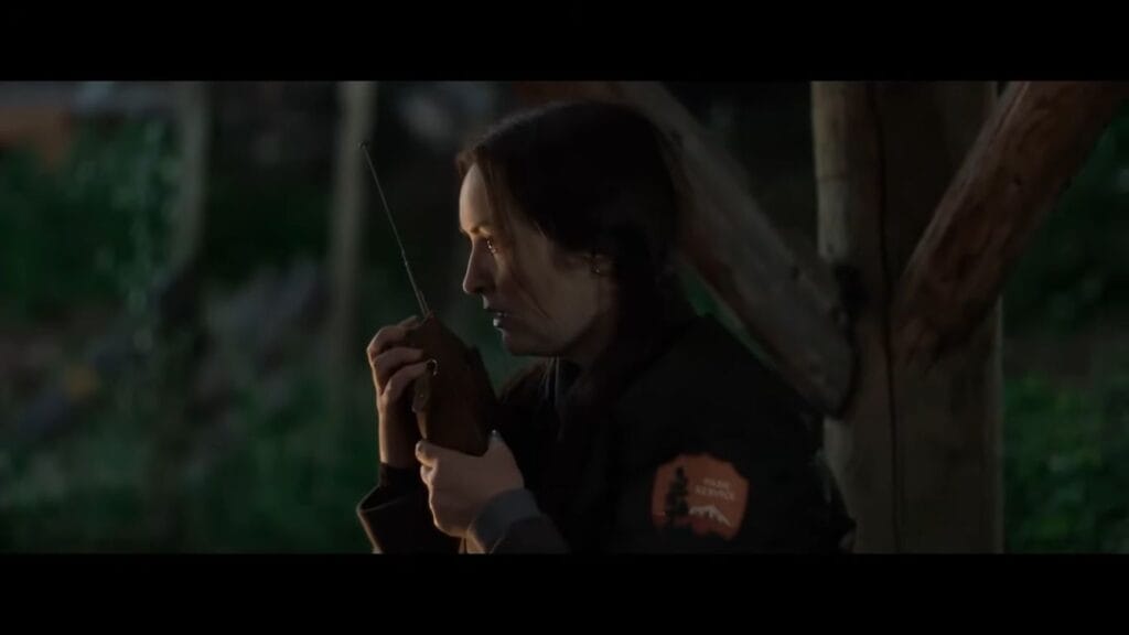 Lauren Call as Ranger Joan looking incredibly tense and anxious while holding a park service radio walkie-talkie in a scene from Grizzly Night.