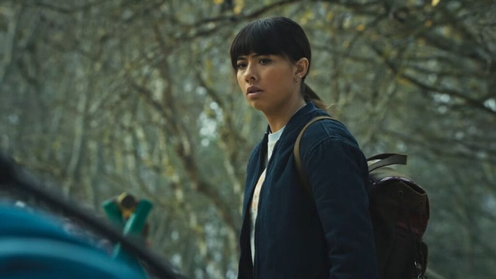 Sasha looking back warily over her shoulder in a wooded setting, a critical frame used to analyze key plot points for a Hive ending explained breakdown.