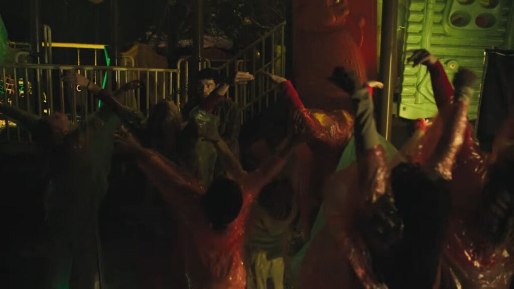 A dark, atmospheric night shot showing a group of figures clad in translucent red rain ponchos raising their arms on a playground structure in Hive.