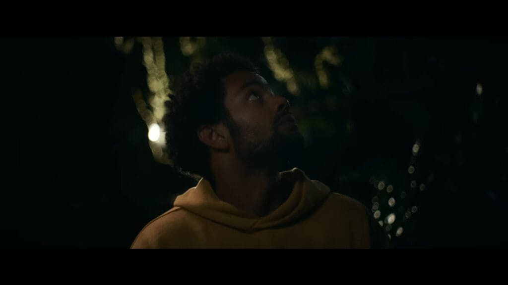A low-angle shot from the horror film Passenger showing Lucas looking up anxiously at night, used to analyse a key scene for a Passenger ending explained article.
