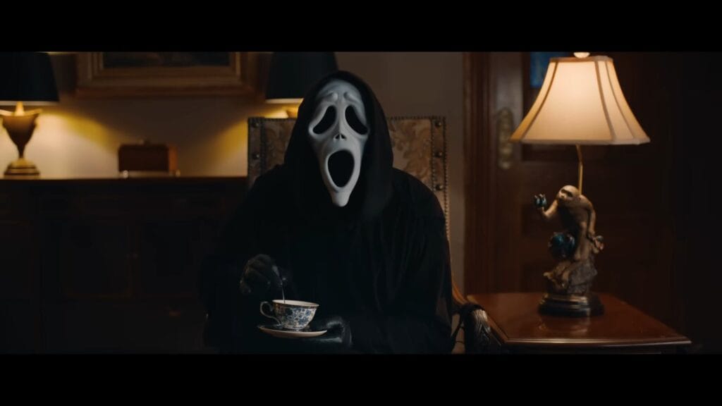 Ghostface sitting in an armchair holding a teacup and saucer in Scary Movie (2026)