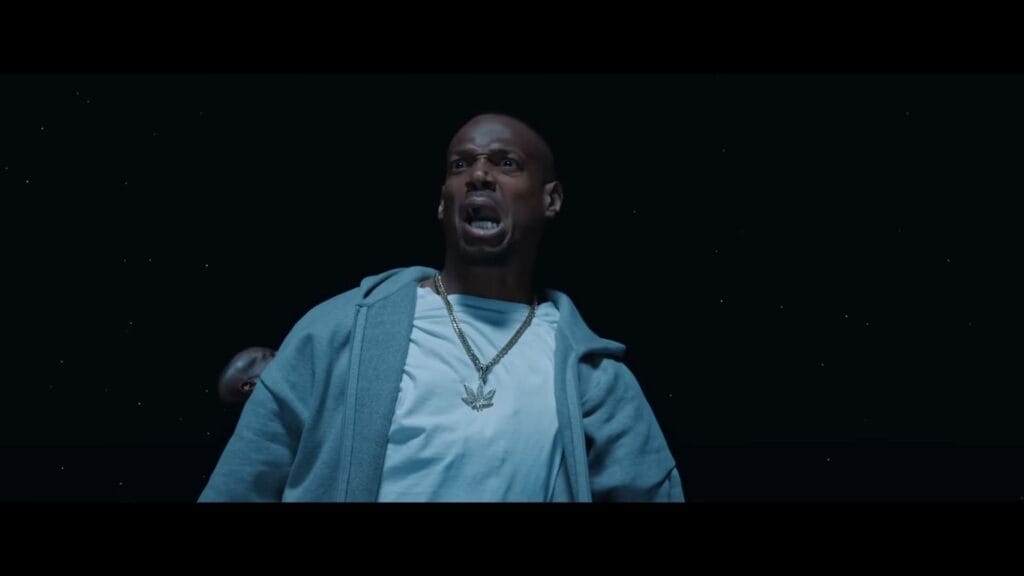 Marlon Wayans as Shorty looking terrified and screaming against a starry dark background in a Get Out parody scene from Scary Movie.