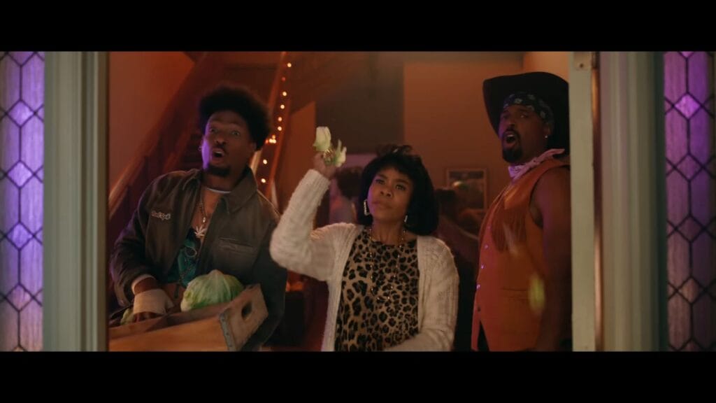 Marlon Wayans, Regina Hall, and Shawn Wayans standing in a doorway looking shocked during a party sequence in Scary Movie.