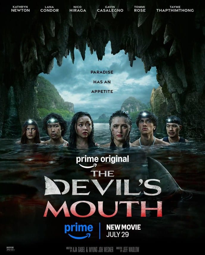 Official Prime Original movie poster for The Devil's Mouth showing six actors wading in bloody water inside a cave with a shark fin lurking nearby under the tagline Paradise Has An Appetite.
