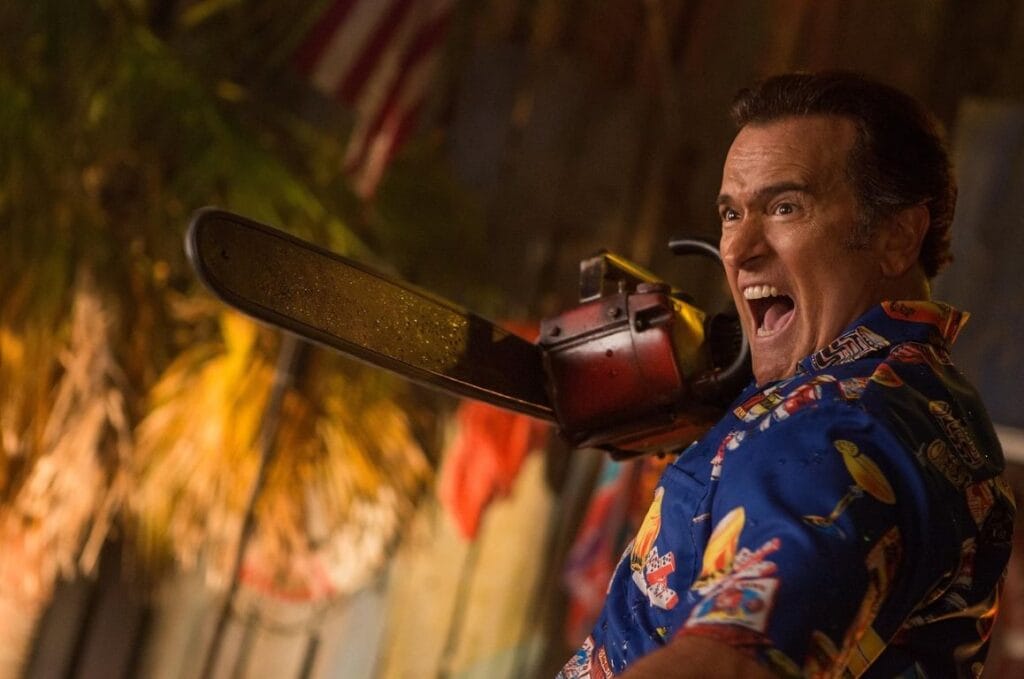 Bruce Campbell as Ash Williams wearing a Hawaiian shirt and yelling wildly while wielding his chainsaw hand in Ash vs Evil Dead.