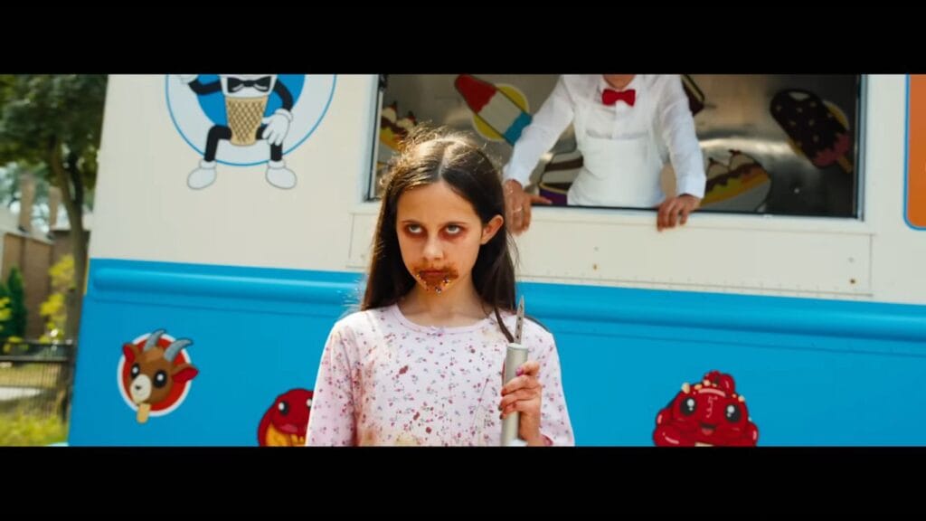 A young girl with chocolate around her mouth holding a knife menacingly in front of the ice cream truck in Ice Cream Man.