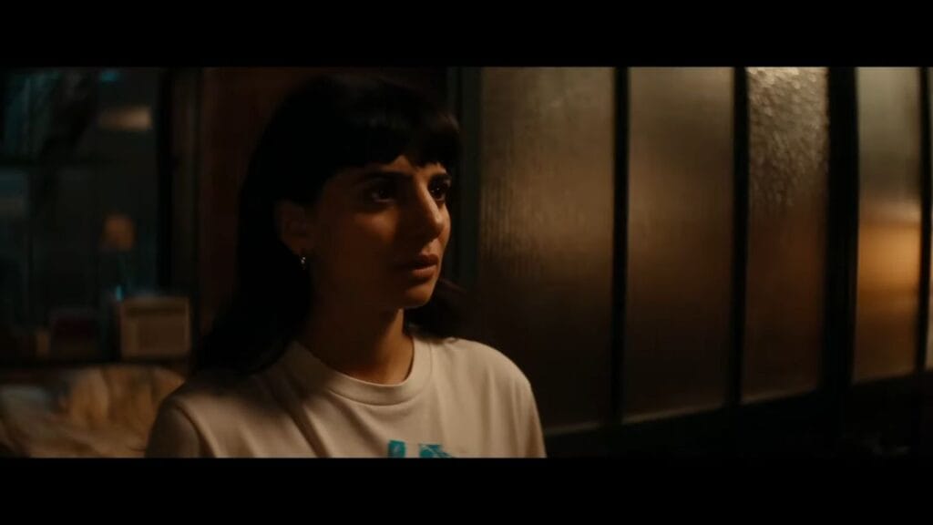 A dark-haired woman looking uneasy while standing in a warmly lit hallway during a scene from Soulm8te.