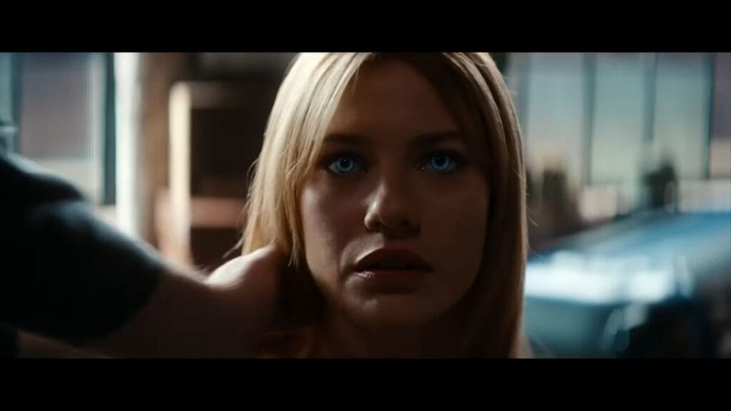 Close-up of Lily Sullivan as Sara staring intently with bright blue eyes as a hand reaches toward her in Soulm8te.