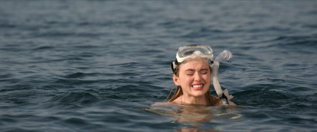 Kathryn Newton wearing a snorkel mask and wincing in pain while swimming in open water in The Devil's Mouth.
