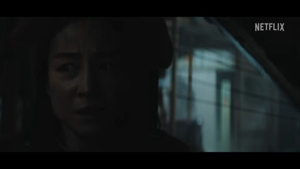 A distressed Greta Lee looking out of a vehicle window at night with a fearful expression in The Last House.