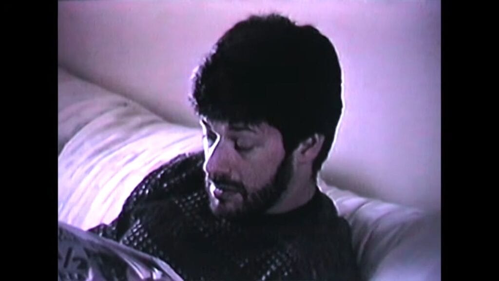 Director and lead actor Robbie Banfitch with a dark beard sitting indoors in a low-resolution camcorder shot from Tinsman Road.