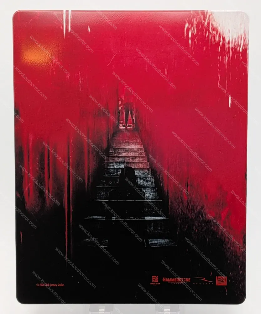 Rear cover artwork of the Barbarian 4K steelbook showing a silhouette descending the red basement stairs towards the Mother waiting in the dark.