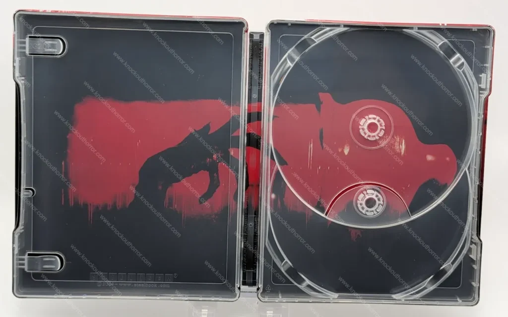 Fully opened interior of the Barbarian steelbook with disc trays empty, revealing the continuous red and black silhouette artwork of a monstrous reaching hand.