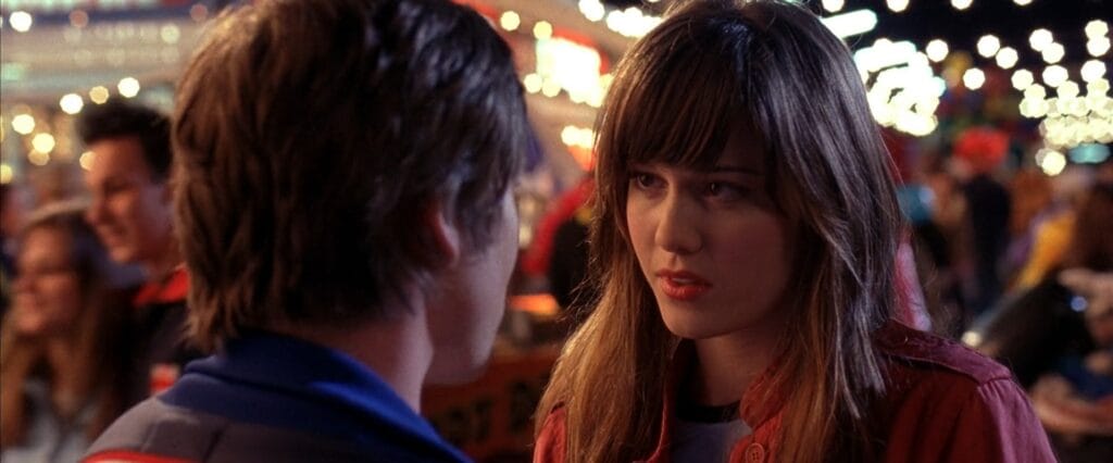 Mary Elizabeth Winstead as Wendy looking anxious while talking to a young man at a brightly lit night-time carnival in Final Destination 3.