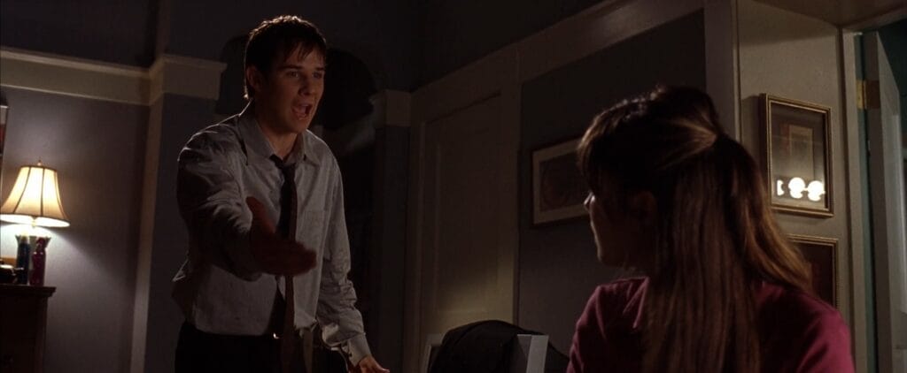 Ryan Merriman as Kevin arguing frantically with an outstretched hand in a dimly lit room in Final Destination 3.
