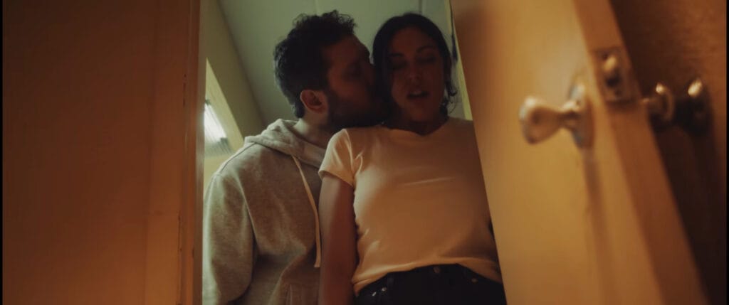 A man threateningly grabbing a woman in an open motel doorway viewed from inside the room in I Know Exactly How You Die.