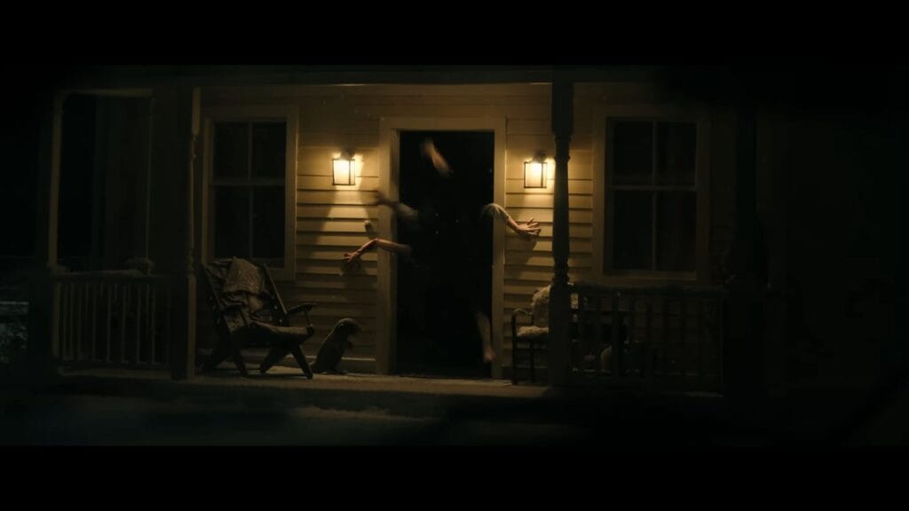 A porch at night with multiple contorted human arms and legs stretching out from an open, pitch-black doorway in Resident Evil.