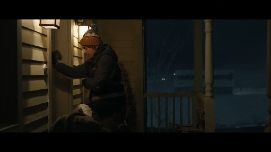 Bryan knocking frantically on the front door of a farm house during a snowy night in Resident Evil.