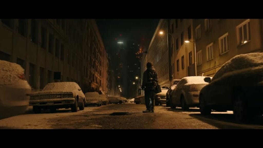 Bryan walking down a snow-dusted, deserted city street lined with parked cars in Resident Evil.