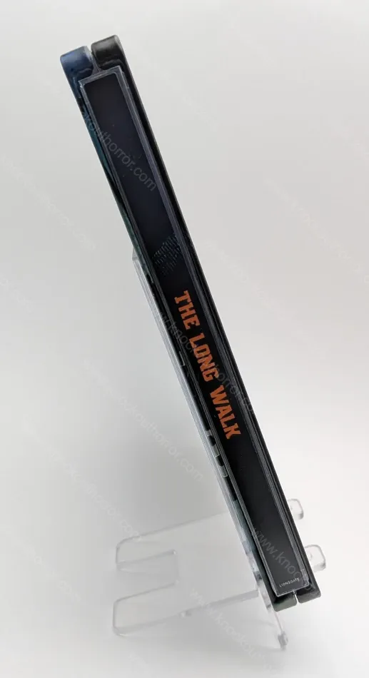 Spine view of The Long Walk 4K steelbook enclosed in its clear plastic slipcover showing the orange title typography.