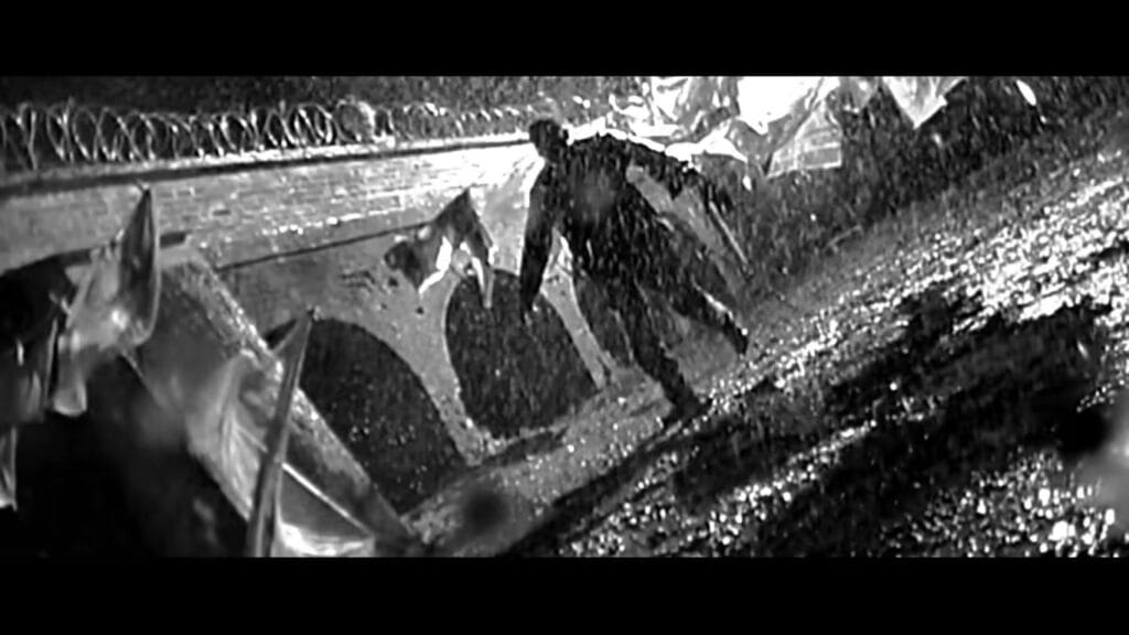 Surveillance camera footage showing a frantic infected person sprinting through a security checkpoint in 28 Days Later.