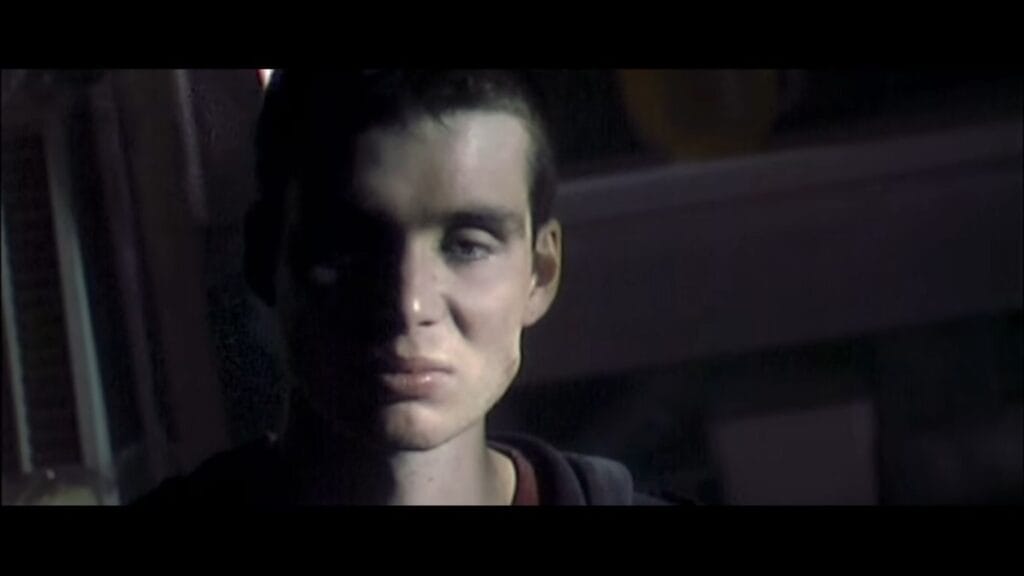 Close-up dramatic portrait of Cillian Murphy as Jim with high contrast shadow across his face in 28 Days Later.